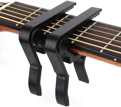 Black guitar capo on an acoustic guitar with a white background